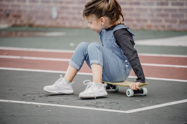 A child sitting on a skateboard at the park