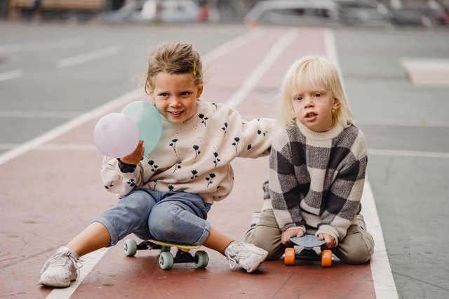 Two young kids sitting on their skateboards